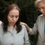 Women praying outdoors, embracing faith and spirituality together intimately.